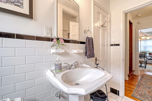 bathroom with wainscoting, a sink, tile walls, and wood finished floors