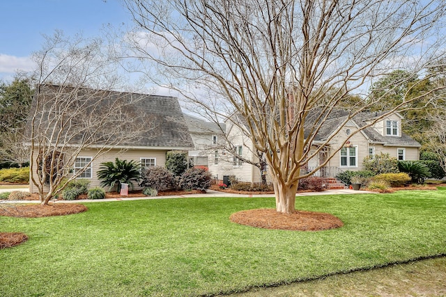 view of front facade with roof with shingles and a front yard