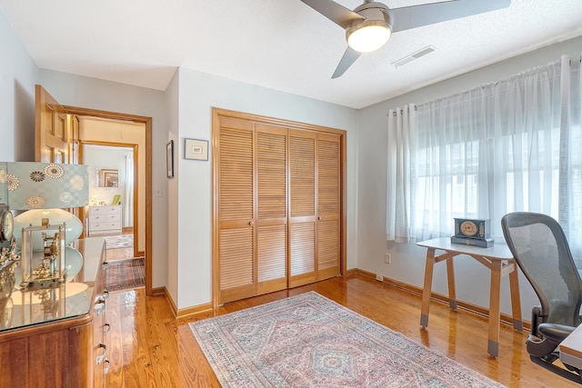 home office featuring a ceiling fan, baseboards, visible vents, and wood finished floors