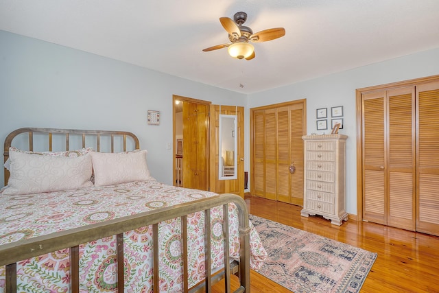 bedroom featuring ceiling fan, baseboards, wood finished floors, and multiple closets