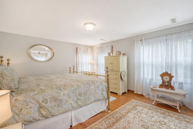 bedroom featuring multiple windows, light wood-type flooring, and visible vents