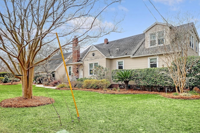 view of front of property featuring a shingled roof and a front yard