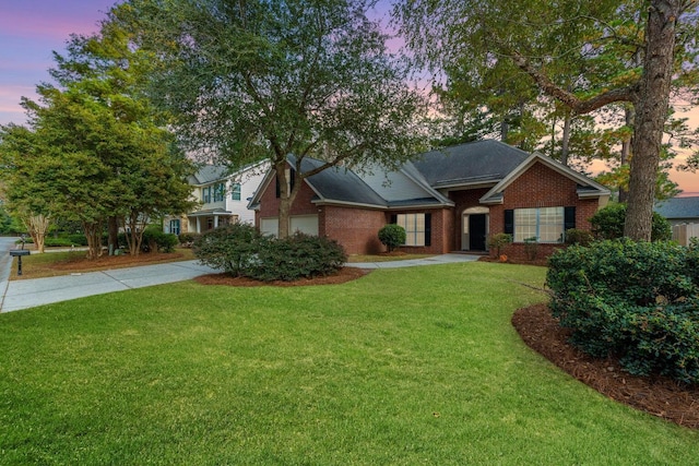 ranch-style house with brick siding, driveway, and a yard