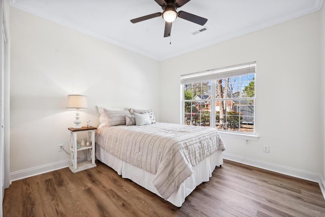 bedroom featuring baseboards, visible vents, wood finished floors, and ornamental molding