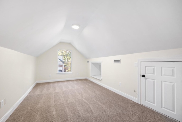 additional living space featuring light carpet, baseboards, lofted ceiling, and visible vents