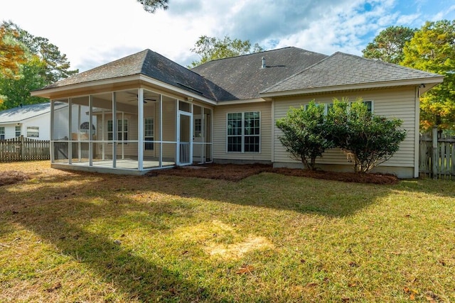 back of property featuring a yard, a sunroom, a shingled roof, and fence