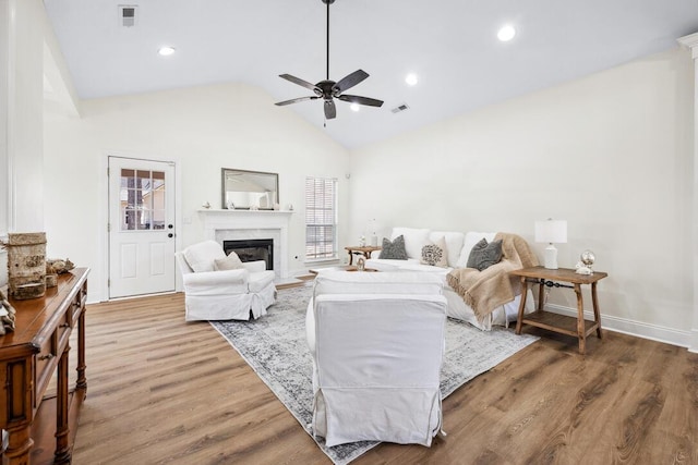 living area featuring visible vents, wood finished floors, ceiling fan, and a fireplace