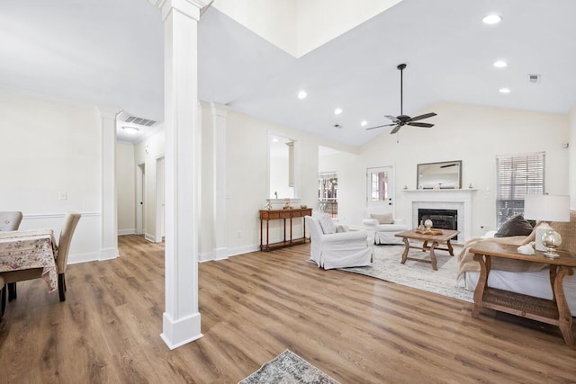 living room featuring decorative columns, a ceiling fan, vaulted ceiling, and wood finished floors