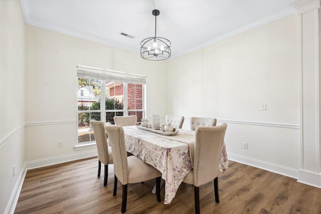 dining area with ornamental molding, wood finished floors, and a notable chandelier