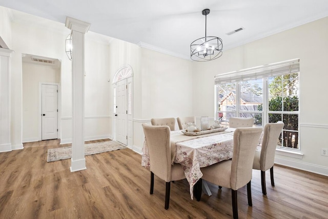 dining space with wood finished floors, a notable chandelier, crown molding, and visible vents