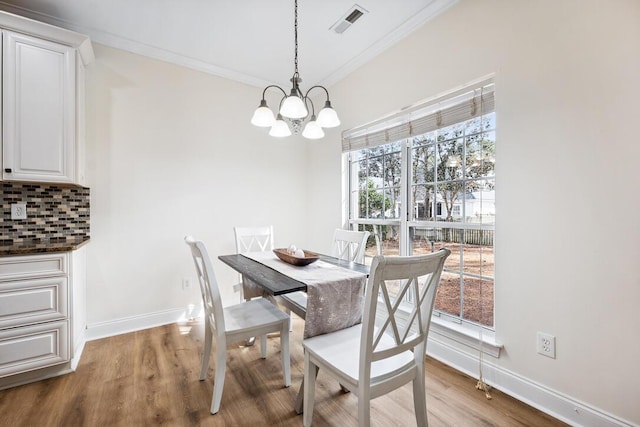 dining area featuring baseboards, crown molding, wood finished floors, and a chandelier