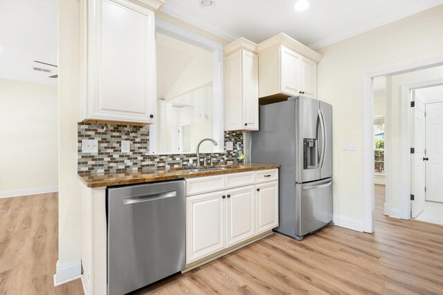 kitchen with light wood-style floors, ornamental molding, backsplash, and stainless steel appliances