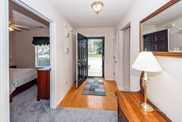 foyer entrance with ceiling fan, a textured ceiling, and light wood-type flooring