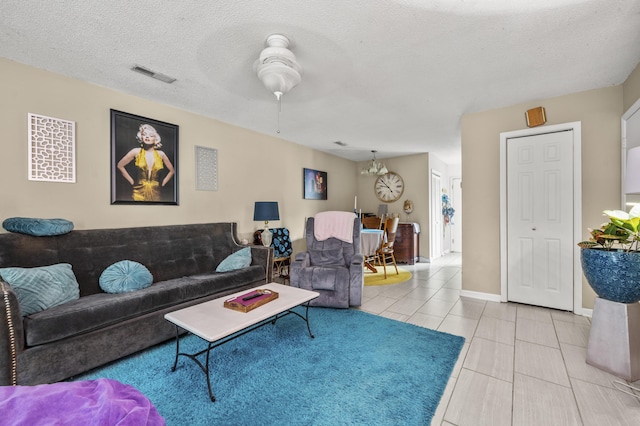 living area featuring visible vents, a textured ceiling, baseboards, and light tile patterned flooring