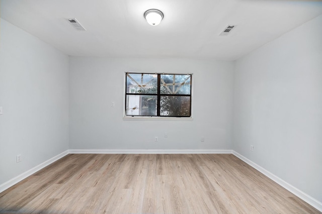 empty room with light wood-type flooring, visible vents, and baseboards