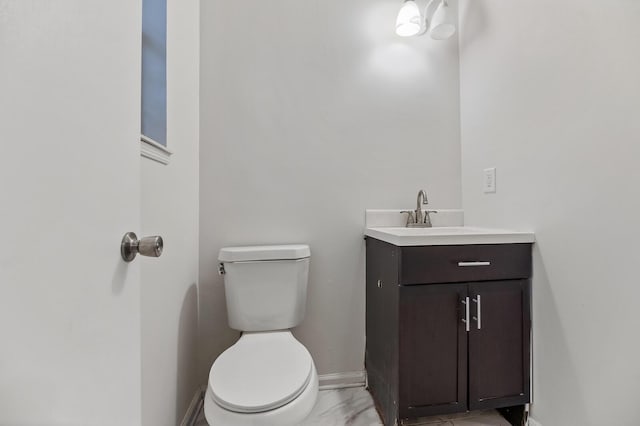 bathroom featuring toilet, marble finish floor, baseboards, and vanity