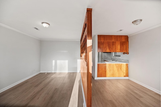 kitchen featuring wood finished floors, visible vents, baseboards, light countertops, and crown molding