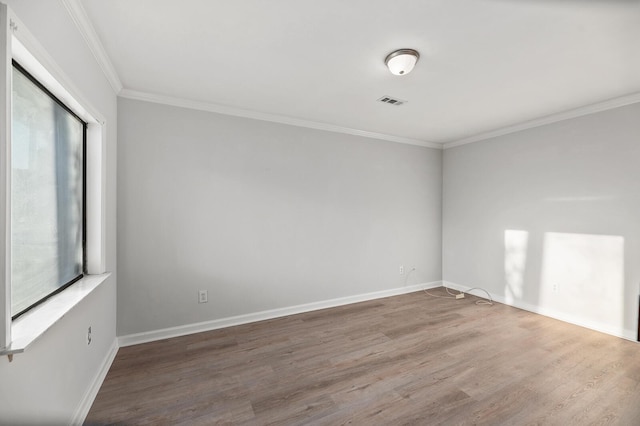 empty room featuring ornamental molding, plenty of natural light, baseboards, and wood finished floors