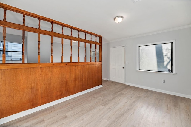 unfurnished room featuring crown molding, light wood-style flooring, and baseboards