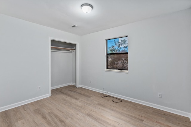 unfurnished bedroom featuring a closet, visible vents, light wood-style flooring, and baseboards