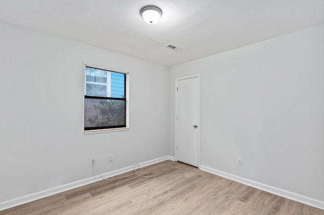 empty room with light wood-style floors, baseboards, and visible vents