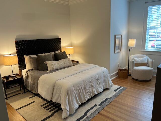 84 Bull St Unit F, Charleston, SC 29401 - bedroom featuring crown molding, multiple windows, light wood-type flooring, and baseboards