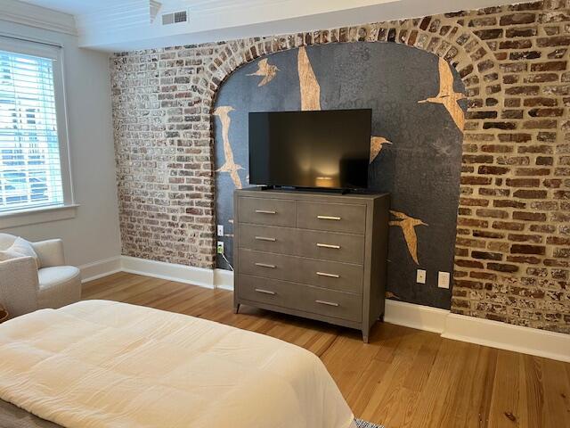 84 Bull St Unit F, Charleston, SC 29401 - bedroom with baseboards, wood finished floors, multiple windows, and brick wall