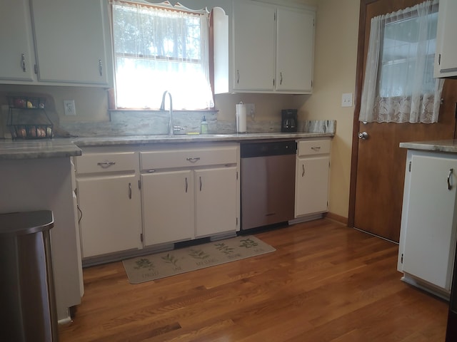 kitchen with light wood finished floors, white cabinetry, light countertops, and stainless steel dishwasher