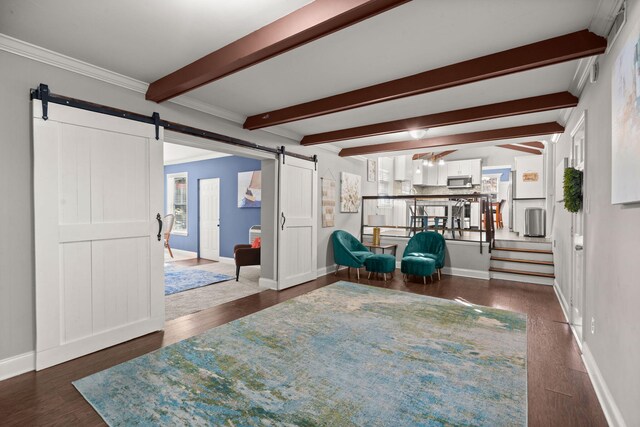 living area featuring beam ceiling, a barn door, dark hardwood / wood-style flooring, and ornamental molding