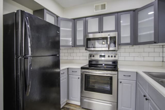 kitchen with tasteful backsplash, visible vents, appliances with stainless steel finishes, and gray cabinetry