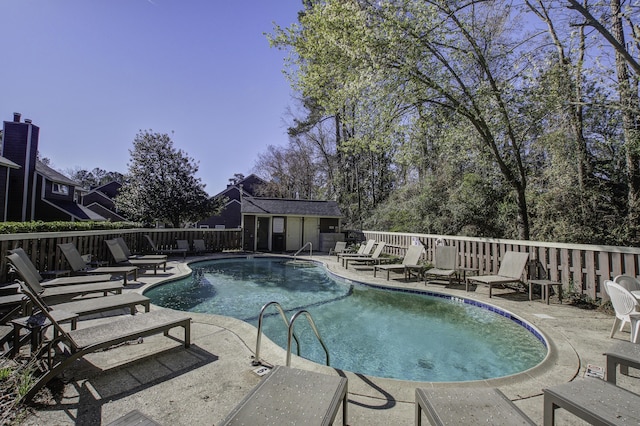 community pool with a patio, fence, and an outdoor structure