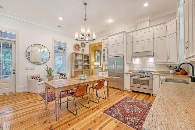 312 Hobcaw Dr, Mount Pleasant, SC 29464 - kitchen featuring appliances with stainless steel finishes, a sink, under cabinet range hood, a chandelier, and ornamental molding