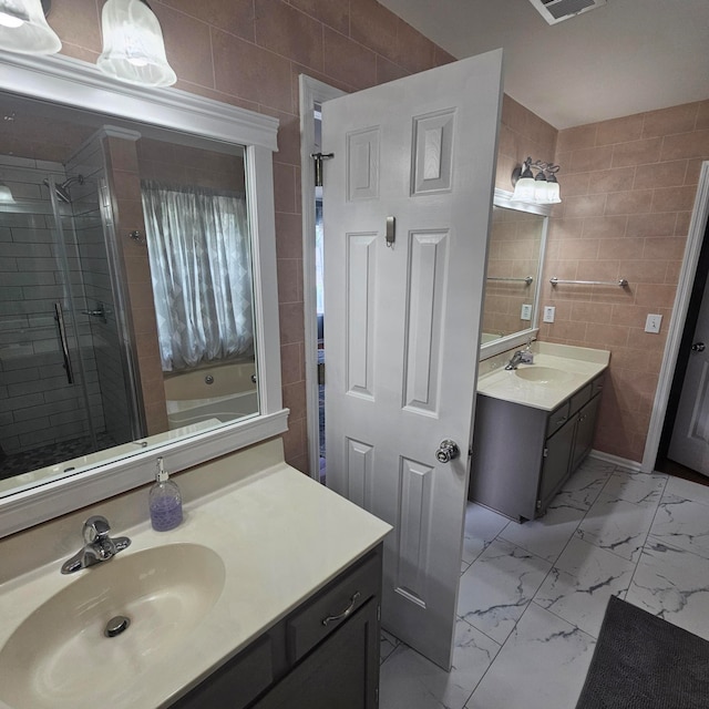 bathroom featuring shower with separate bathtub, vanity, and tile walls