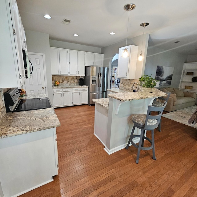 kitchen featuring light stone counters, hanging light fixtures, light hardwood / wood-style flooring, white cabinetry, and stainless steel appliances