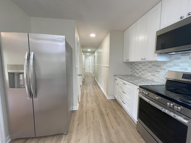 kitchen featuring stainless steel appliances, light wood-style flooring, decorative backsplash, white cabinets, and light stone countertops