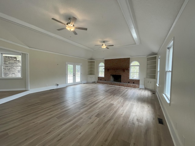 unfurnished living room featuring ceiling fan, wood finished floors, visible vents, french doors, and a brick fireplace