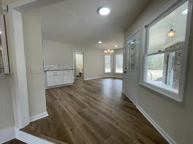 interior space with baseboards, dark wood-style flooring, a textured ceiling, a notable chandelier, and recessed lighting