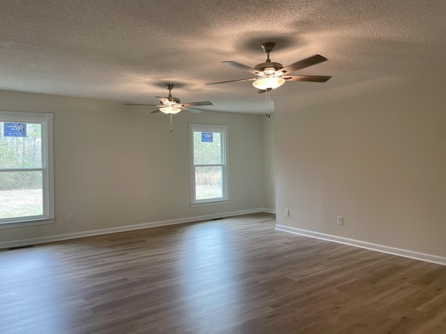 spare room featuring baseboards, dark wood-style flooring, and a healthy amount of sunlight