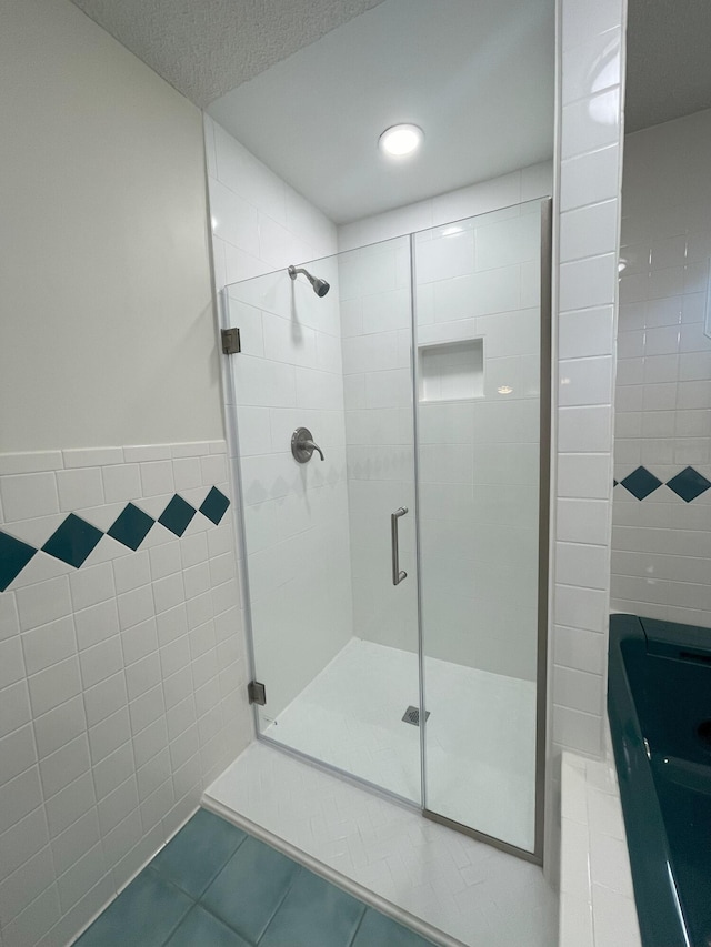 full bathroom with a stall shower, tile walls, and tile patterned floors