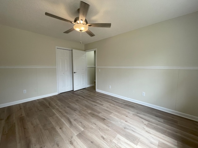 unfurnished bedroom with a textured ceiling, ceiling fan, wood finished floors, and baseboards