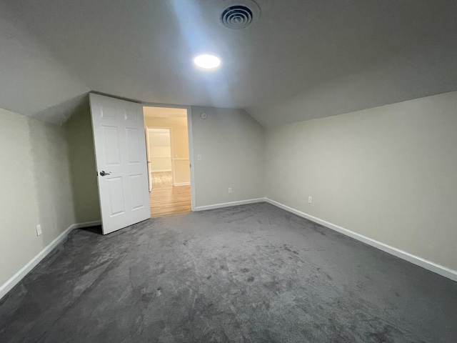 bonus room with lofted ceiling, visible vents, dark carpet, and baseboards