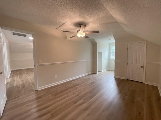 additional living space with ceiling fan, a textured ceiling, visible vents, and wood finished floors