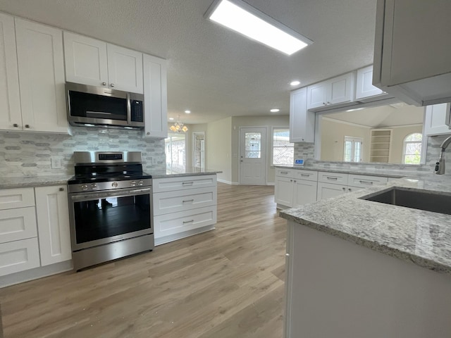 kitchen with appliances with stainless steel finishes, white cabinets, and decorative backsplash