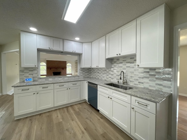 kitchen featuring light wood-style floors, white cabinets, a sink, and stainless steel dishwasher