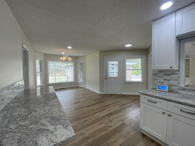 kitchen featuring dark wood-style flooring, backsplash, white cabinets, a textured ceiling, and baseboards