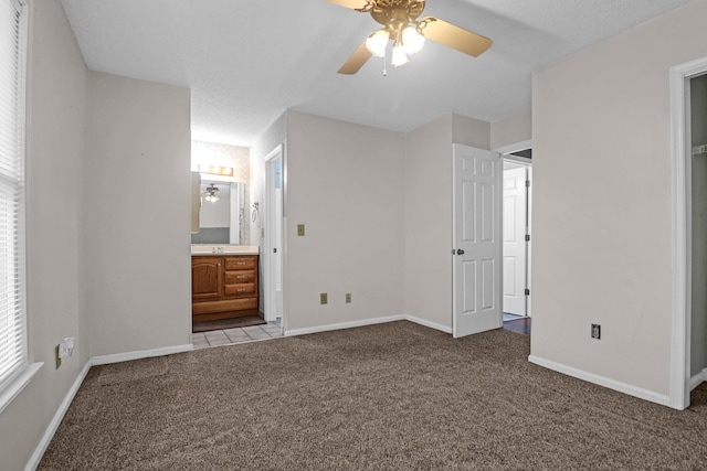 unfurnished bedroom featuring light colored carpet, ensuite bath, and ceiling fan