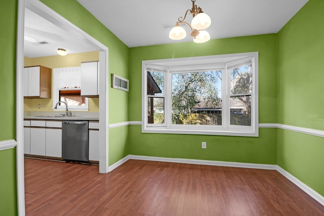 kitchen featuring white cabinetry, sink, hanging light fixtures, stainless steel dishwasher, and a chandelier