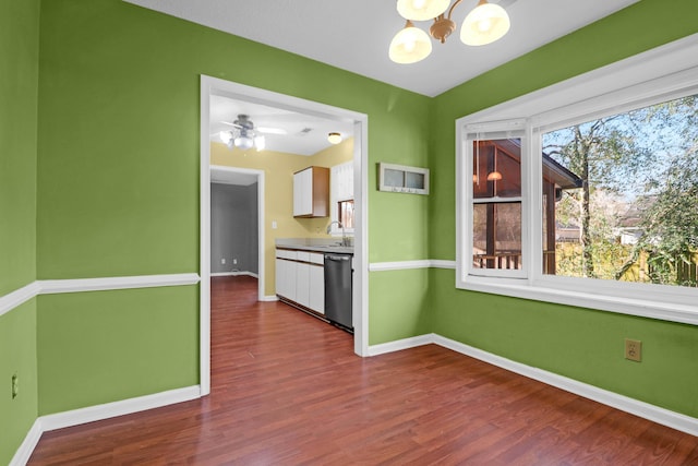 unfurnished dining area with sink, ceiling fan with notable chandelier, and hardwood / wood-style flooring