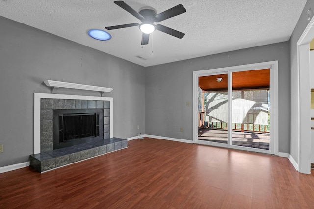 unfurnished living room with ceiling fan, a fireplace, wood-type flooring, and a textured ceiling