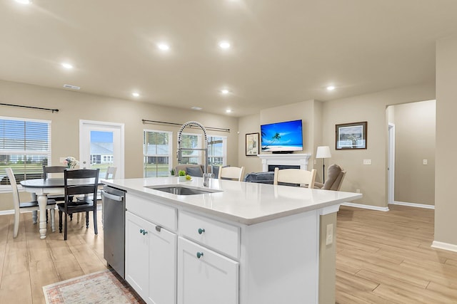 kitchen with light hardwood / wood-style floors, a center island with sink, sink, white cabinets, and dishwasher